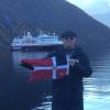 Past Commodore Jon Klestadt holds the burgee on his Norway adventure