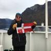 Past Commodore Jon Klestadt holds the burgee on his Norway adventure