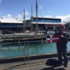 PC Tony Spencer holds the burgee in Auckland, NZ with classic yacht Waitangi in the background